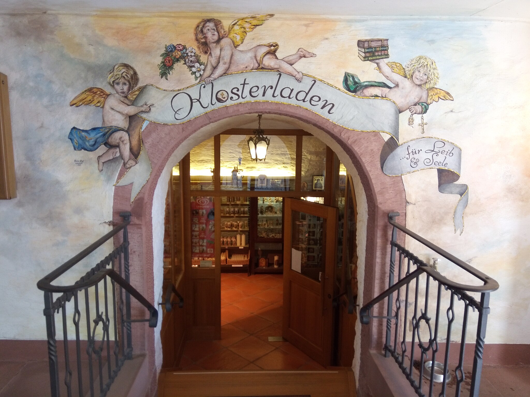 Eingang zum Klosterladen des Klosters Engelberg: Durch einen mit L&uuml;ftelmalerei verzierten Eingang f&uuml;hrt der Weg einige Stufen hinunter ins Souterrain.